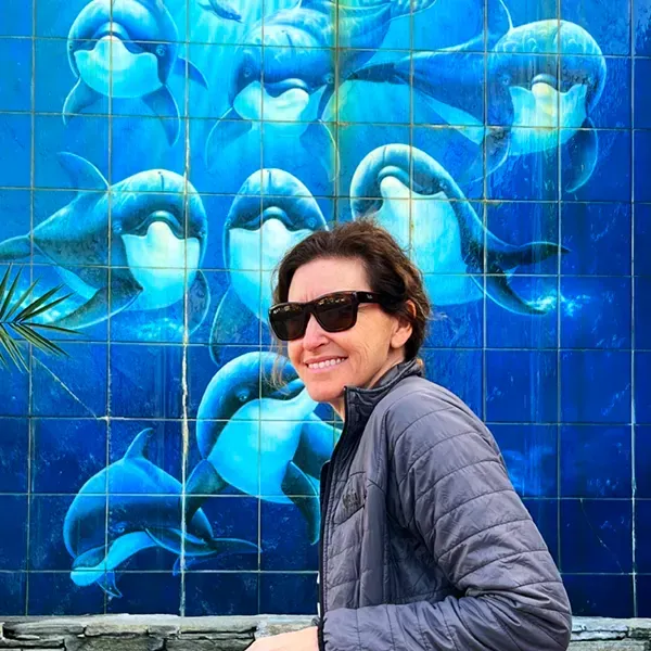 A woman in front of the dolphin mural at Wyland art gallery in Laguna