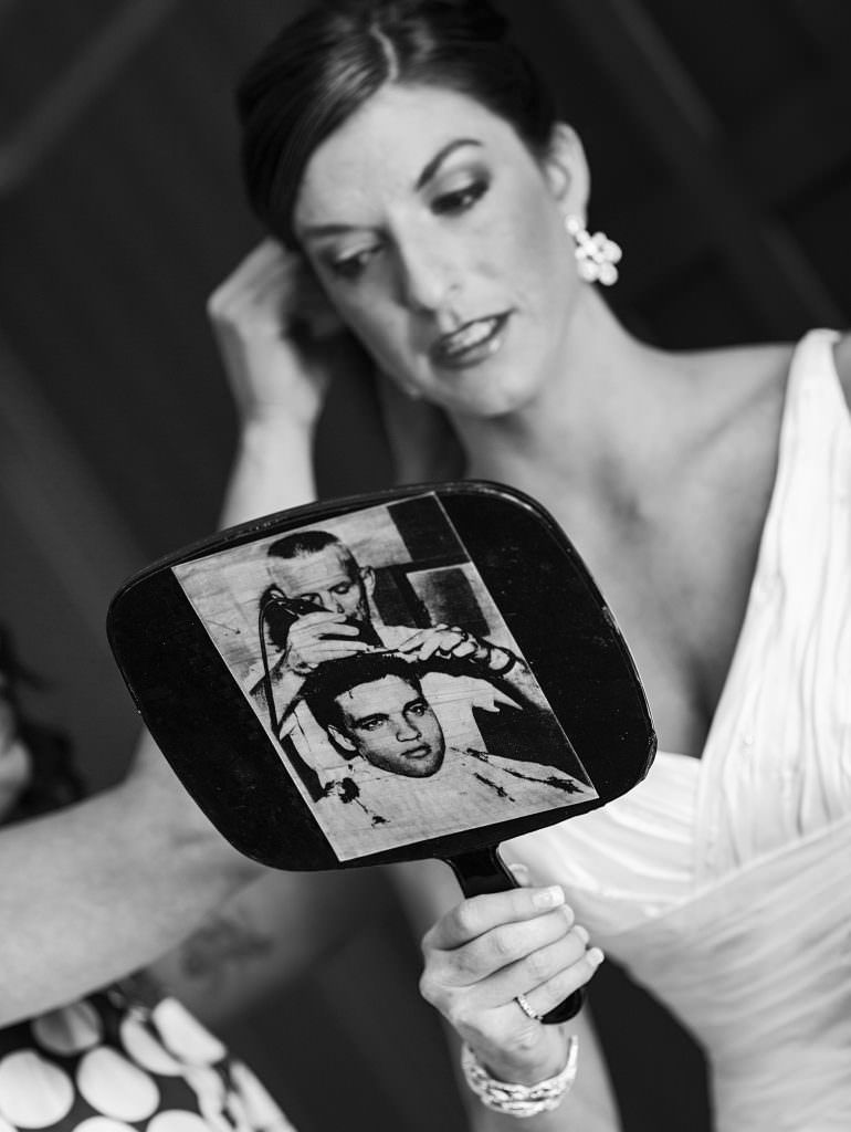 A bride is looking at herself in a hand mirror