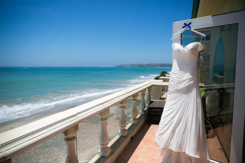 A wedding dress is hanging on a balcony overlooking the ocean in Orange County.