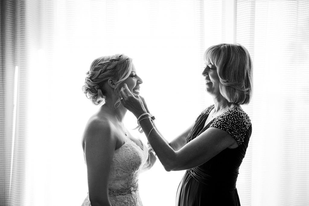 A black and white photo of a bride and her mother getting ready for her wedding at Hyatt Huntington Beach.