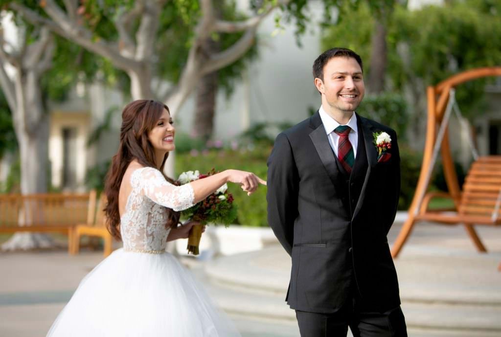 A bride and groom are standing next to each other and the bride is pointing at the groom.