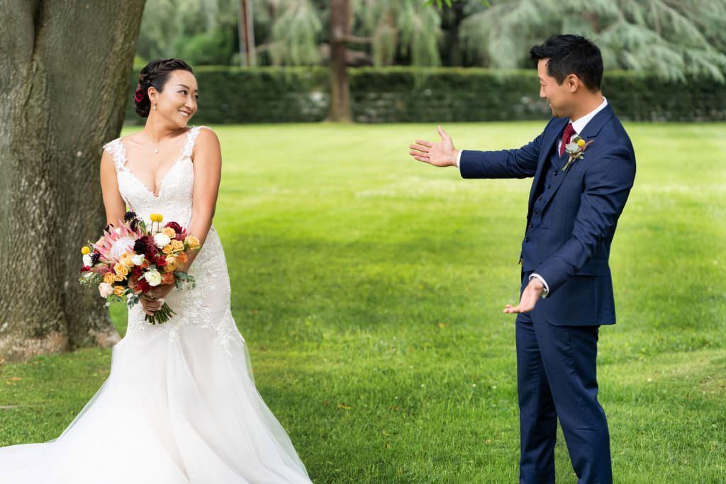 A bride reveals her dress to her group before their wedding in a grassy field