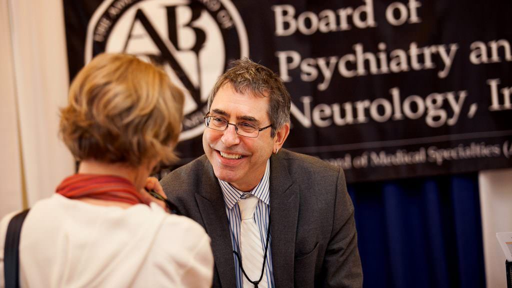Candid Event Photos A man and woman are talking in front of a sign that says board of psychiatry and neurology