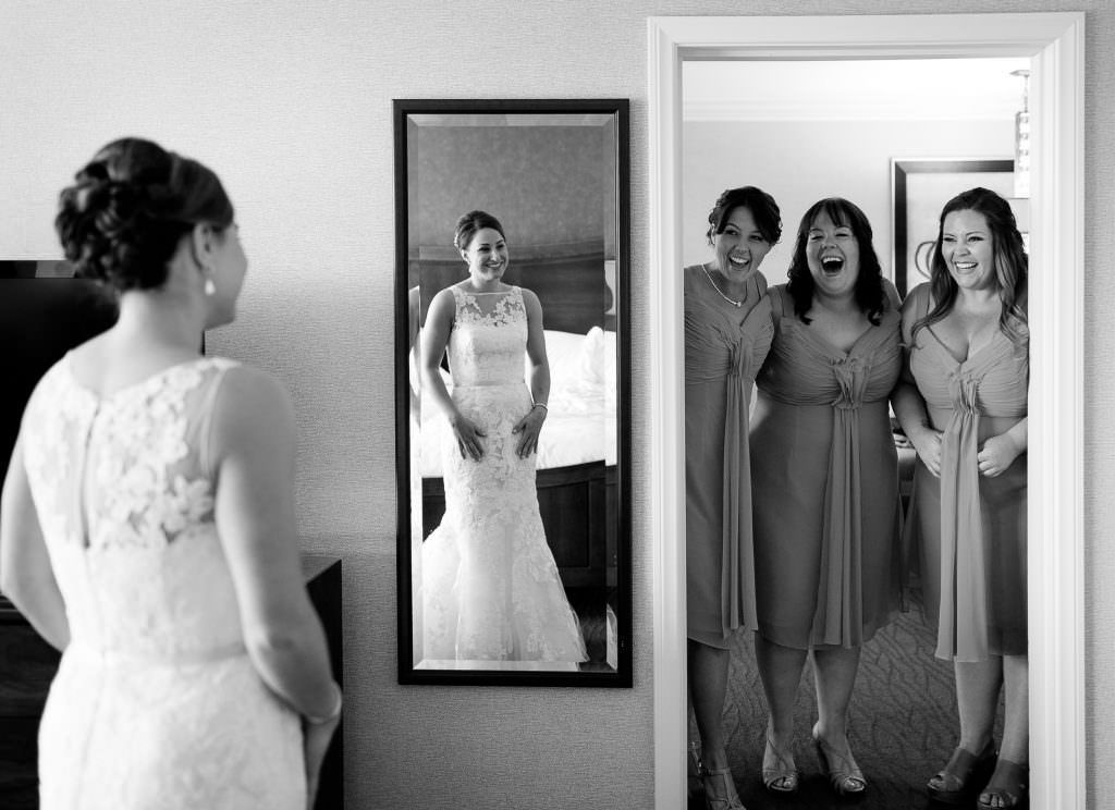 A bride and her bridesmaids are looking at their reflection in a mirror in Costa Mesa HIlton.