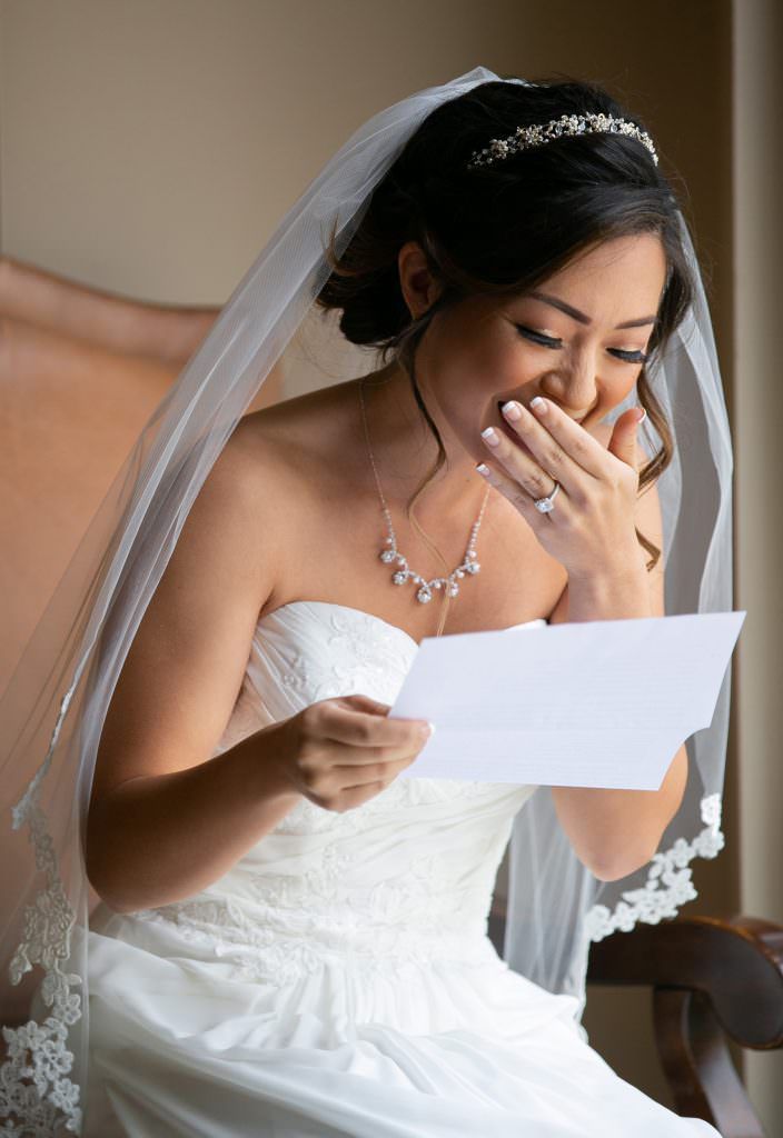 A bride in a wedding dress is reading a letter from her groom Waterfront Hilton in Huntington Beach