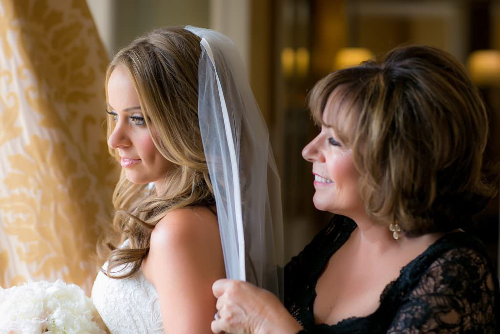 A mother is helping a bride put on her veil in Laguna Beach.