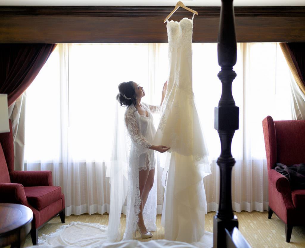 A bride is putting on her wedding dress in a hotel room at Balboa Bay Resort in Newport Beach