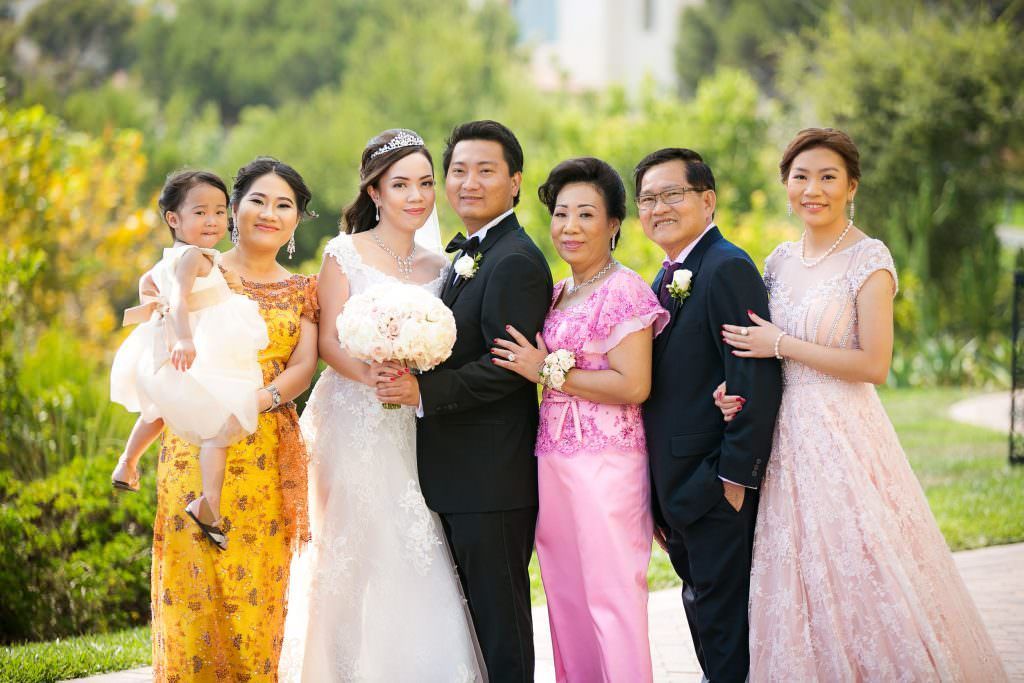 A bride and groom are posing for a picture with their family at Terranea Resort.