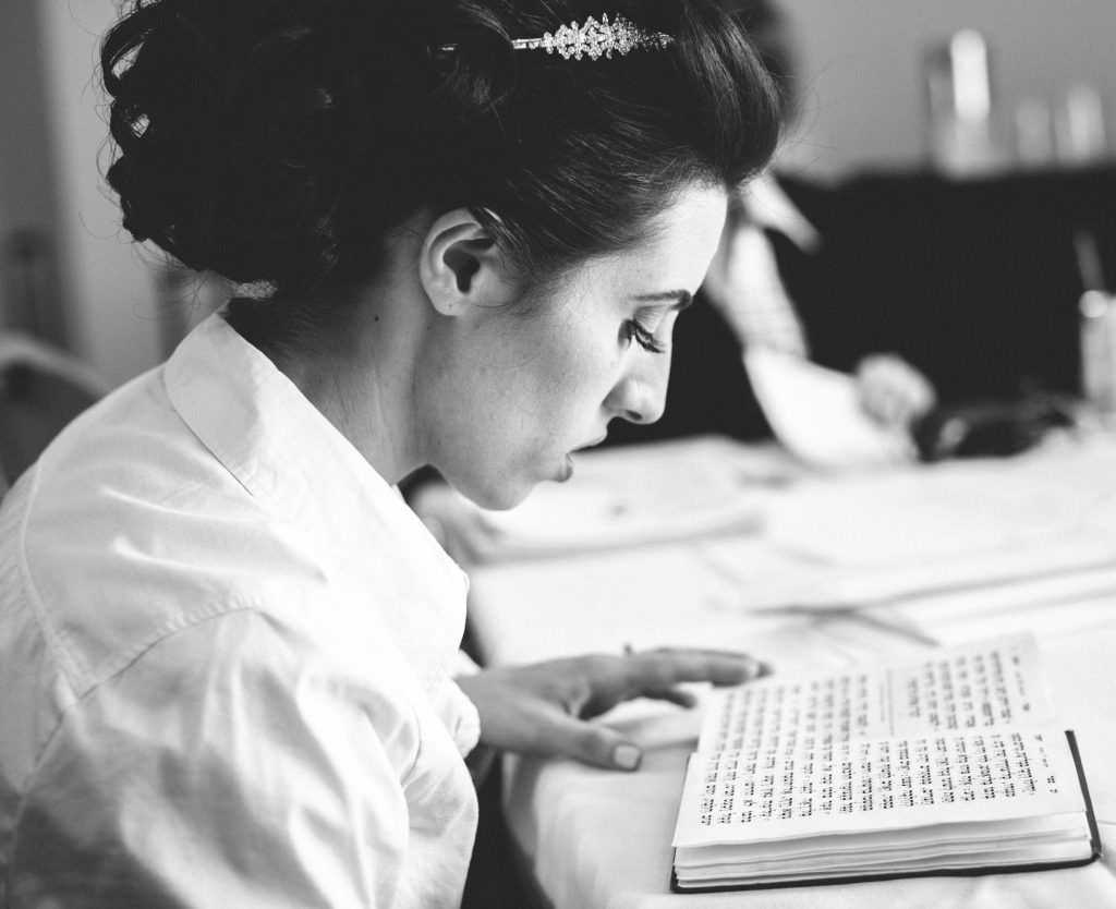 A jewish bride is sitting at a table reading prayers