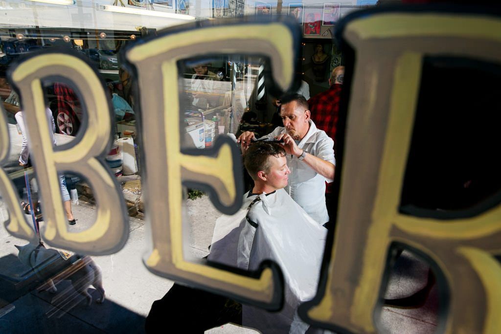 A groom is getting his hair cut at a barber shop.