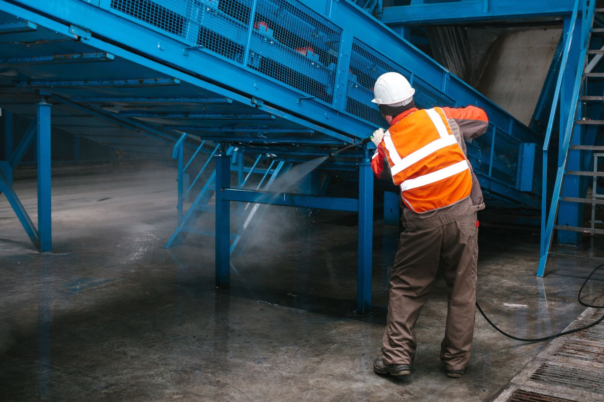 Worker on lift pressure washing red building exterior. Worker on lift pressure washing red building exterior.