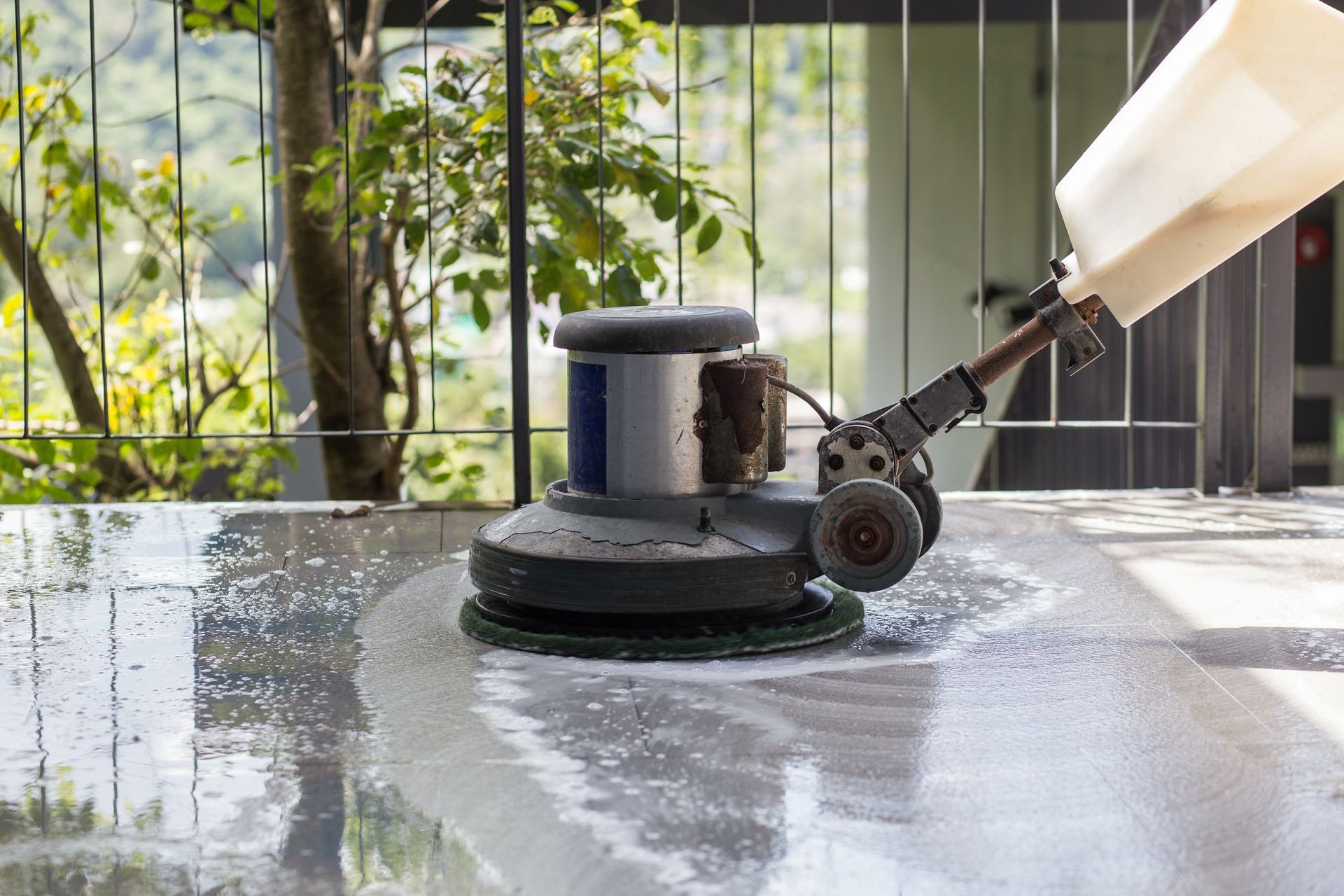Floor cleaning machine scrubbing a concrete surface, spraying water. Floor cleaning machine scrubbing a concrete surface, spraying water.