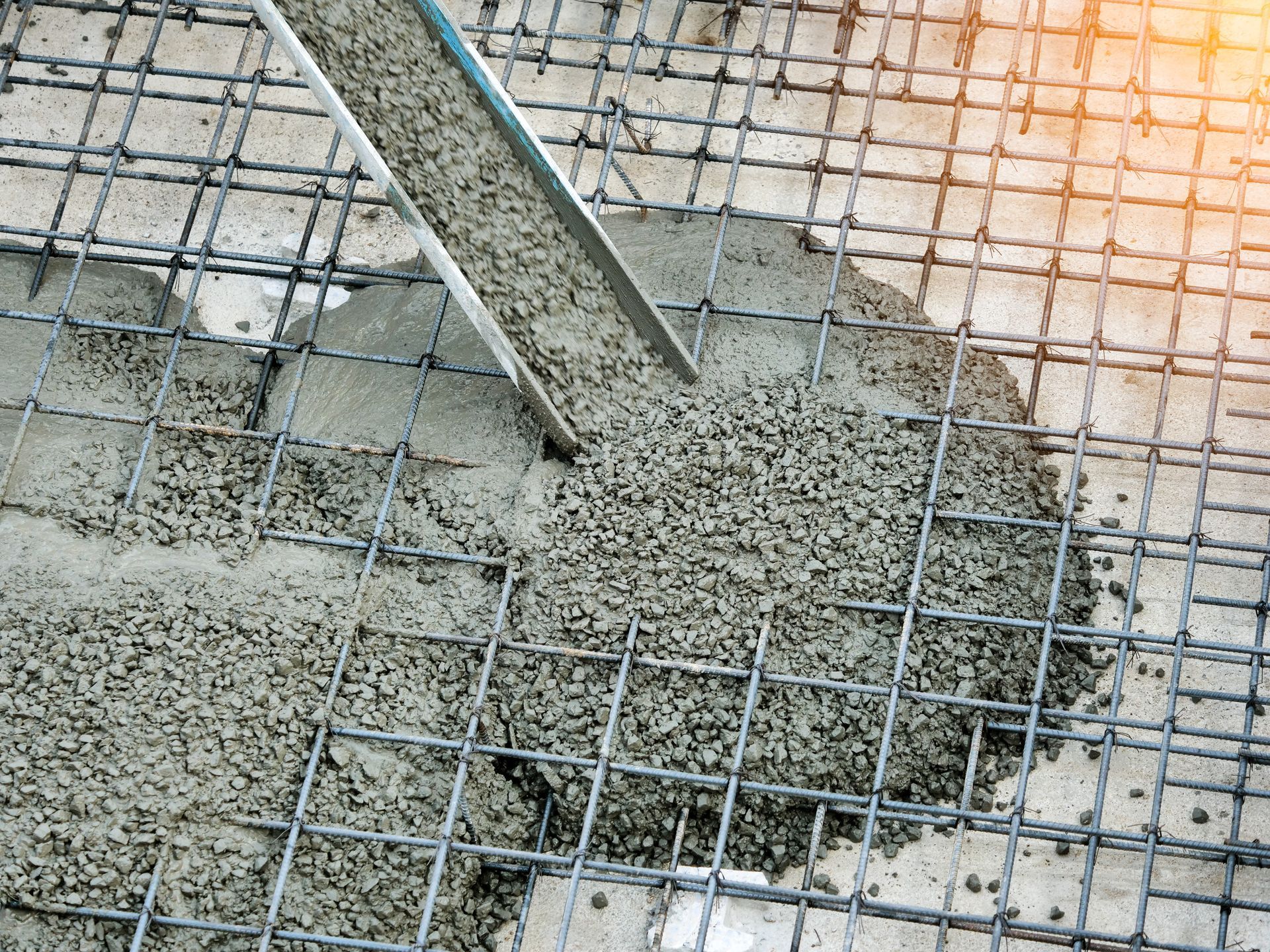 Concrete being poured over metal rebar grid.