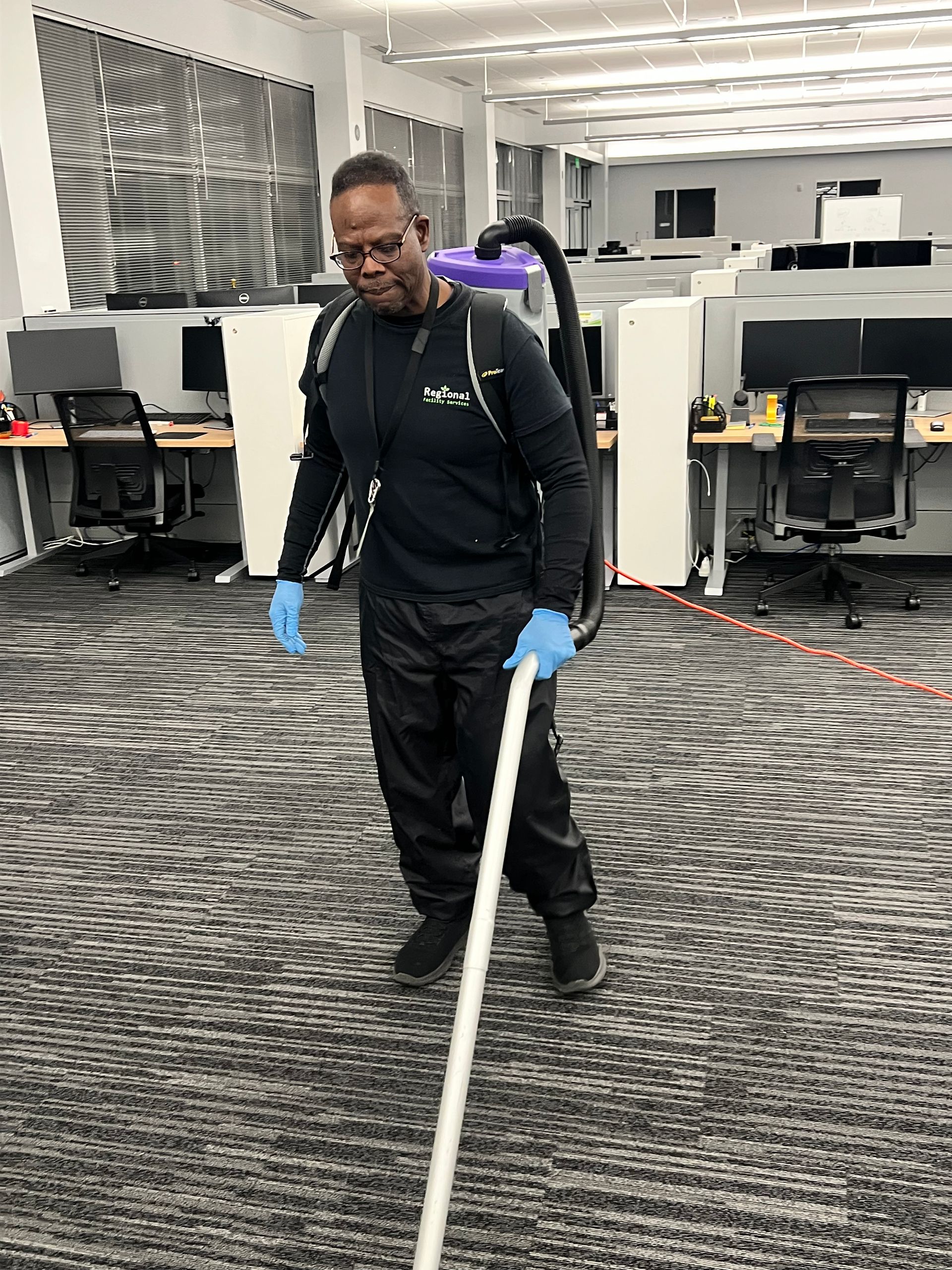Person in blue scrubs mops a hospital room floor, yellow caution sign nearby. Person in blue scrubs mops a hospital room floor, yellow caution sign nearby.