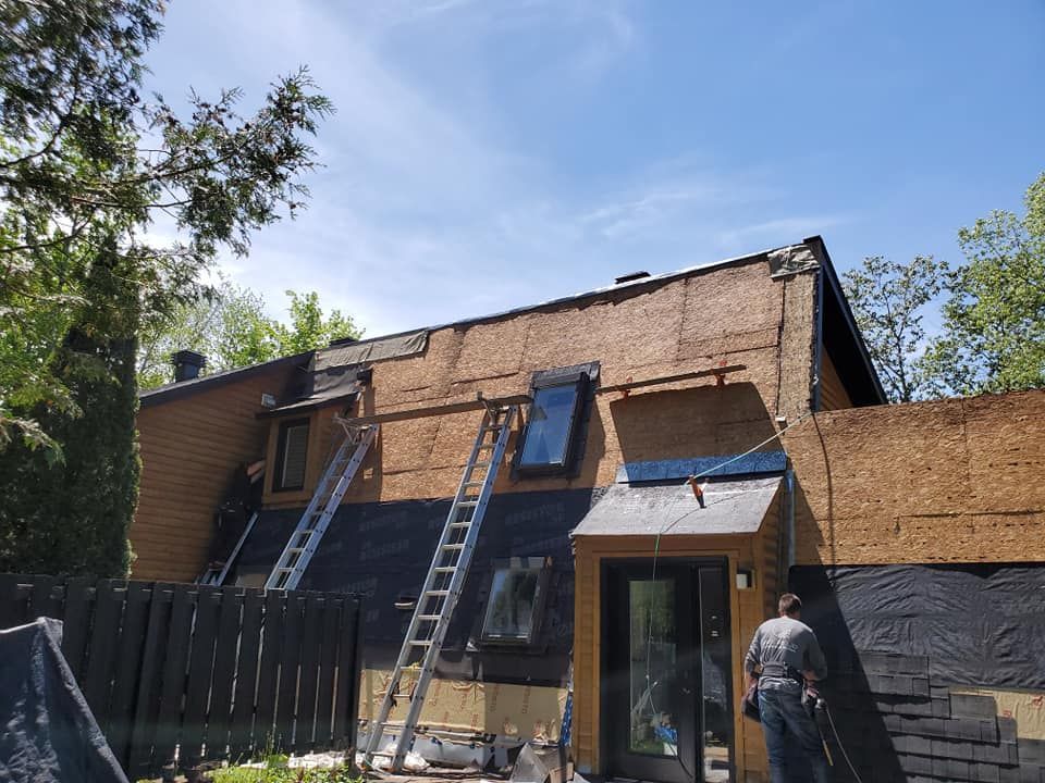 Réparation du toit d'une maison à deux étages. Échelles appuyées contre la charpente, ouvrier devant une porte.