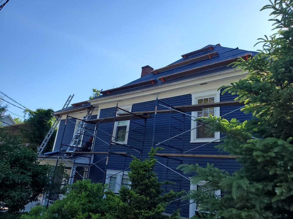 Extérieur de la maison avec bardage bleu foncé et échafaudages, en construction.