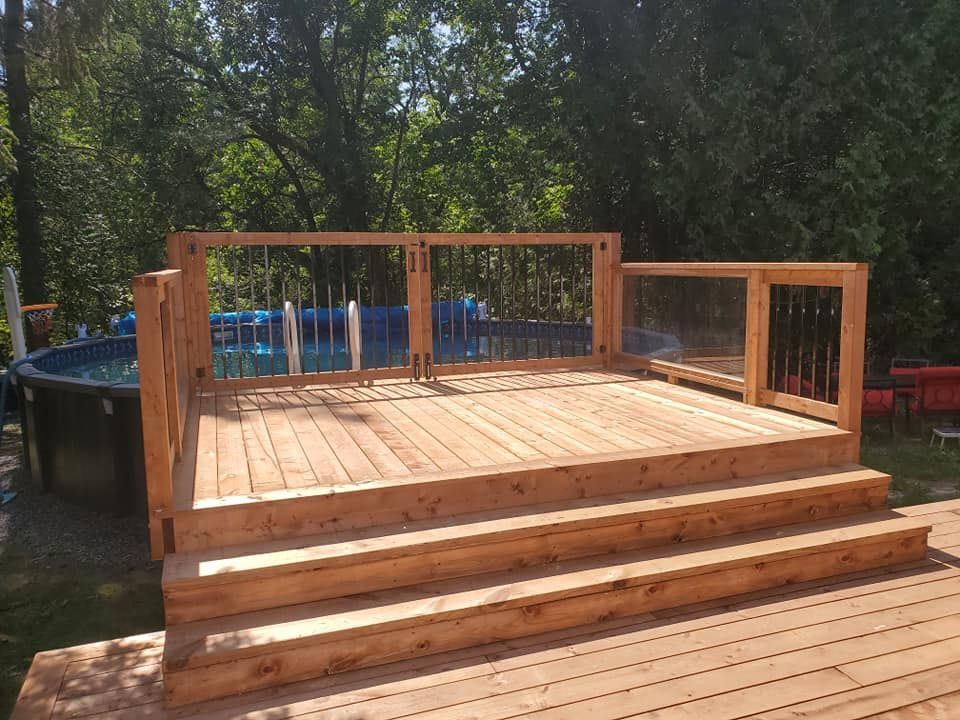 Terrasse en bois avec escalier, jouxtant la piscine. La terrasse est dotée d'une rambarde en verre et en bois.