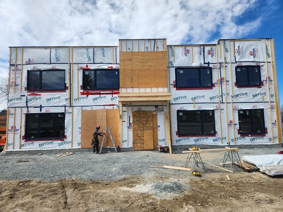 Construction d'un bâtiment de deux étages. Un ouvrier se trouve près de l'entrée.