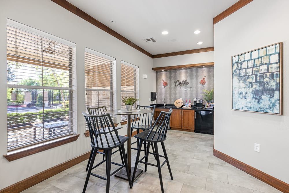 Apartment resident lounge with a table and chairs in it and a painting on the wall at Marquis at The Woodlands in Spring, TX.