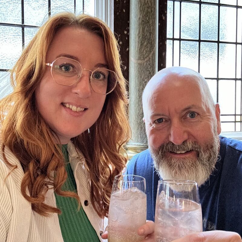 A man and a woman are sitting at a table holding glasses of water.