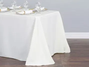 A table with a white tablecloth and plates and glasses on it.