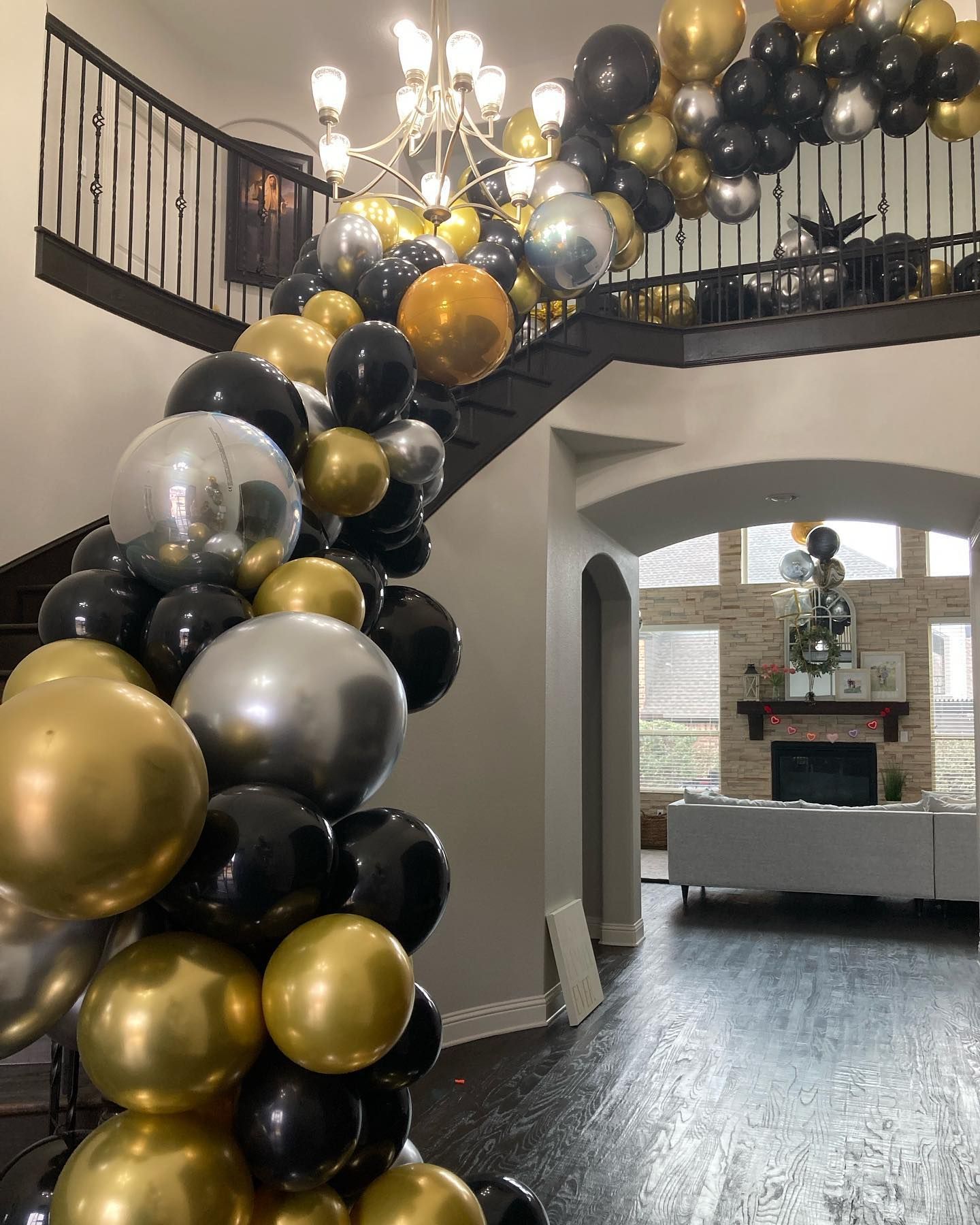 A bunch of balloons are hanging from the ceiling in a living room.
