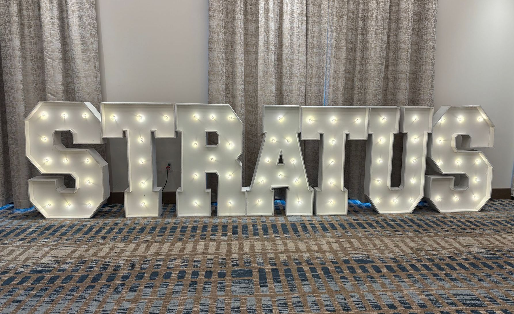 A large lighted sign that says stratus is sitting on the floor.