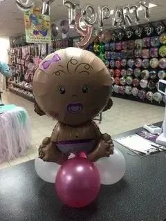 A baby balloon is sitting on top of a pink balloon.