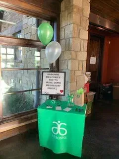 A green table with balloons and a sign on it in a room.