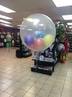 A large clear balloon filled with balloons in a store.