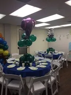 A room with tables and chairs and balloons on the ceiling.