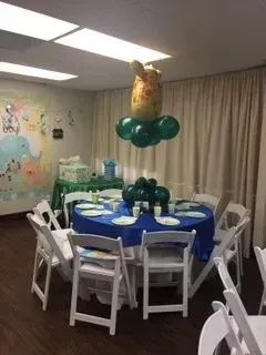 A room with tables and chairs and balloons hanging from the ceiling.