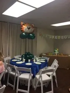 A room with tables and chairs and a tiger balloon hanging from the ceiling.