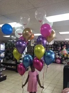 A little girl is holding a bunch of balloons in a store.