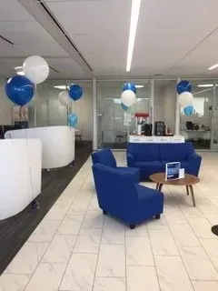 A living room with blue chairs , a couch , a table and balloons.