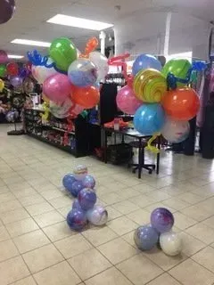A bunch of balloons are sitting on the floor in a store.