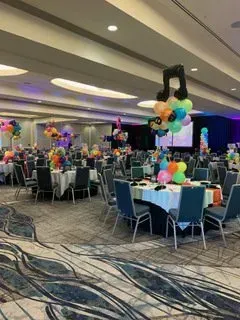 A large room filled with tables and chairs decorated with balloons.