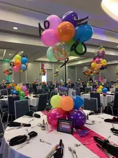 A room with tables and chairs and balloons hanging from the ceiling.