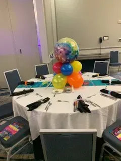 A table with a bunch of balloons on it in a room.
