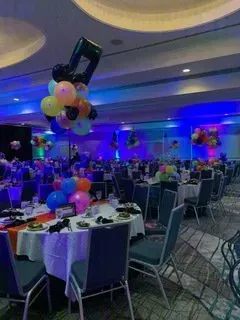 A large room filled with tables and chairs and balloons.