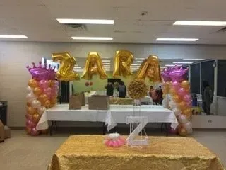 A room decorated with balloons and crowns for a birthday party.