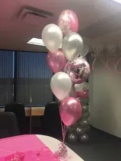 A bunch of pink and white balloons are sitting on top of a table.