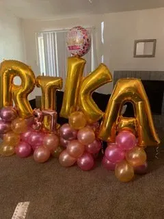 A bunch of balloons are sitting on the floor in a living room.