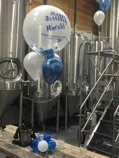 A bunch of balloons are sitting on a table in a brewery.