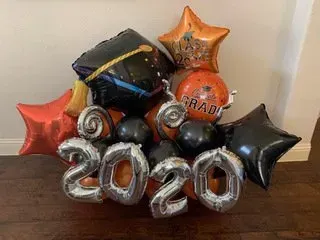 A bunch of graduation balloons are sitting on a wooden floor.