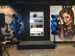 A room with balloons and a painting of a man and a woman on the wall.