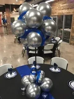 A large room with tables and chairs and balloons on the ceiling.