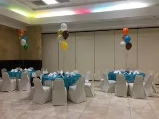 A room with tables and chairs and balloons on the wall.