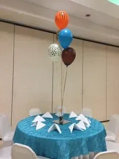 A table with a blue tablecloth and balloons on it
