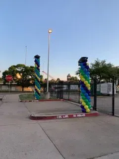 Two columns made of balloons are in a parking lot.